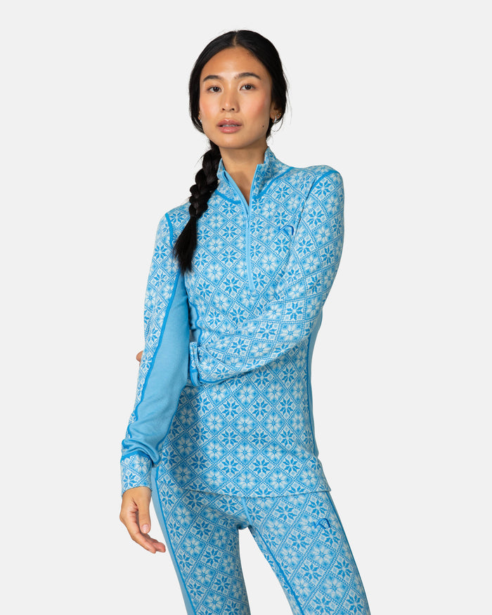 Women's half-zip base layer top with blue snowflake pattern, front view on model