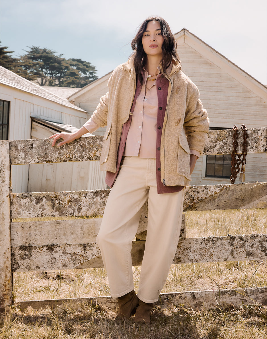 Women's oversized boucle coat in warm sandy beige, worn open over layered outfit, front view