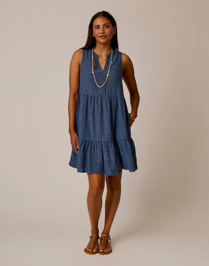 Sleeveless tiered mini dress with v-neck and small polka dot pattern, styled with necklace