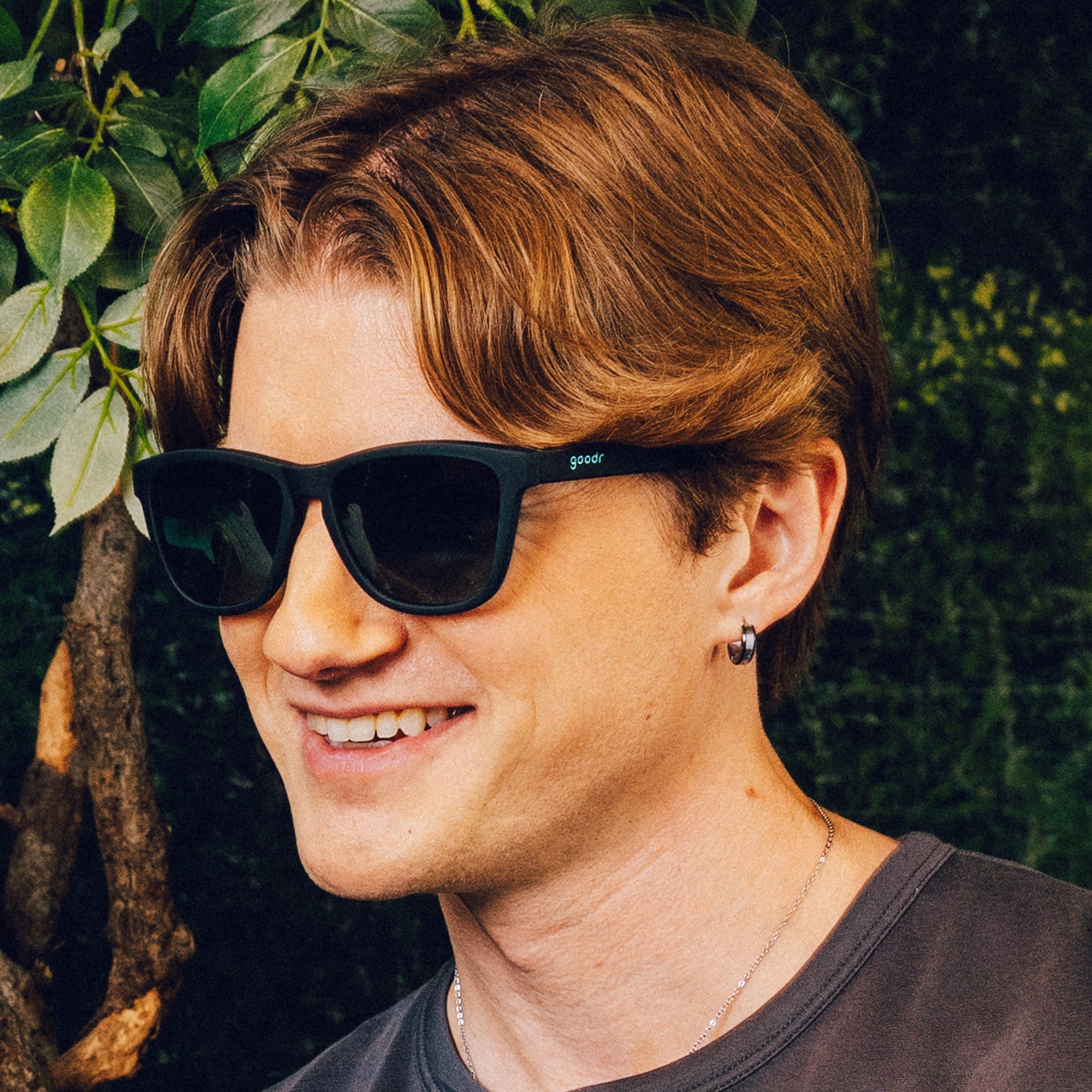 Black sunglasses with dark lenses worn by person in outdoor setting