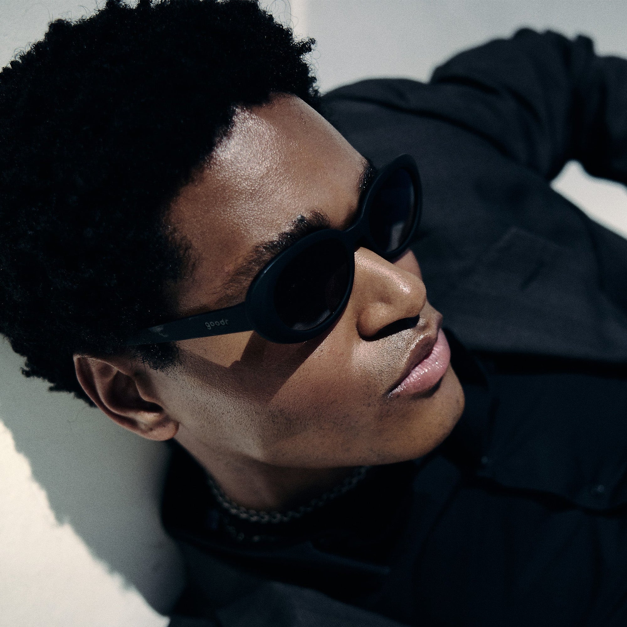 Black wraparound sunglasses worn by person in profile view against neutral background
