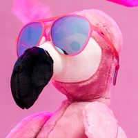 Pink aviator sunglasses with blue mirrored lenses on plush flamingo toy