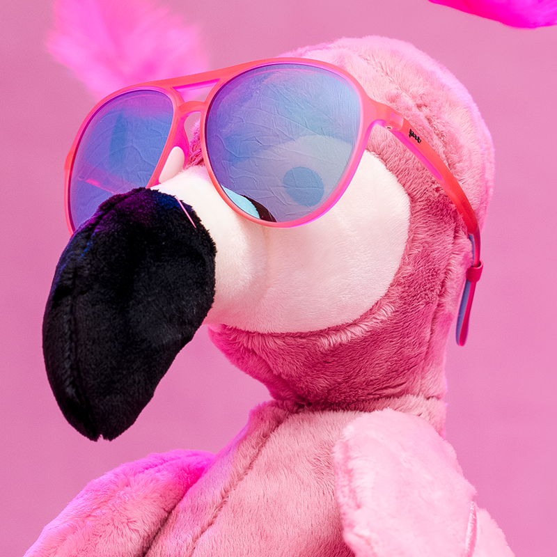 Pink aviator sunglasses with blue mirrored lenses on plush flamingo toy