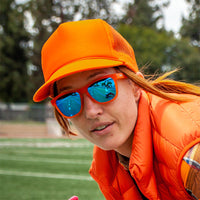 Blue mirrored sunglasses worn by person in orange outfit outdoors