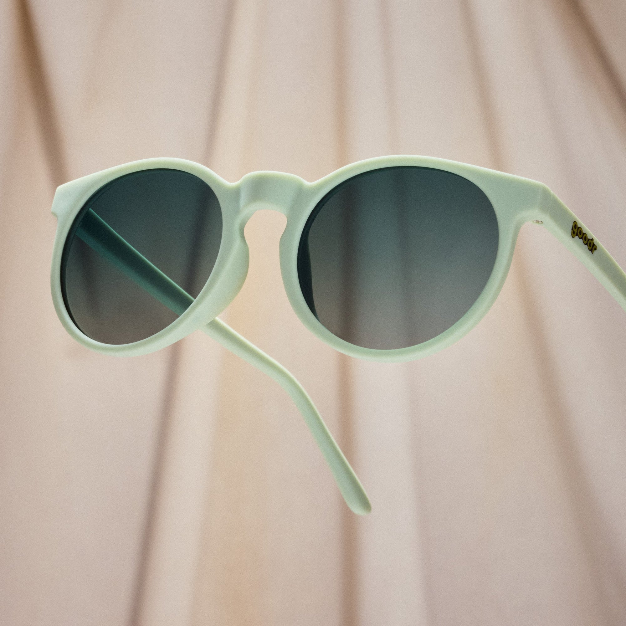 Round mint green sunglasses with gradient dark lenses on light wooden background