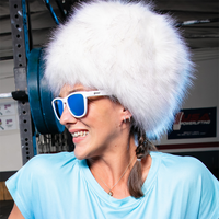 White frame sunglasses with blue mirrored lenses worn by smiling person in furry hat