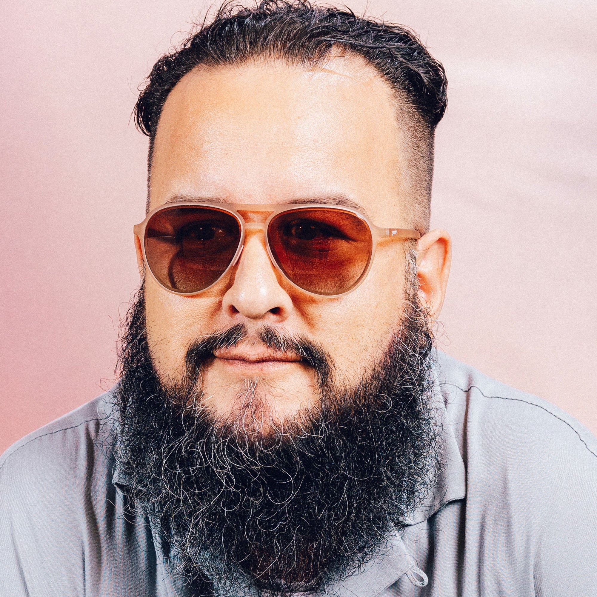 Orange translucent aviator sunglasses with brown gradient lenses worn by bearded man