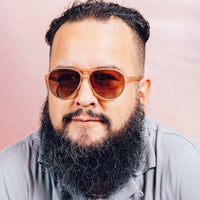 Orange translucent aviator sunglasses with brown gradient lenses worn by bearded man