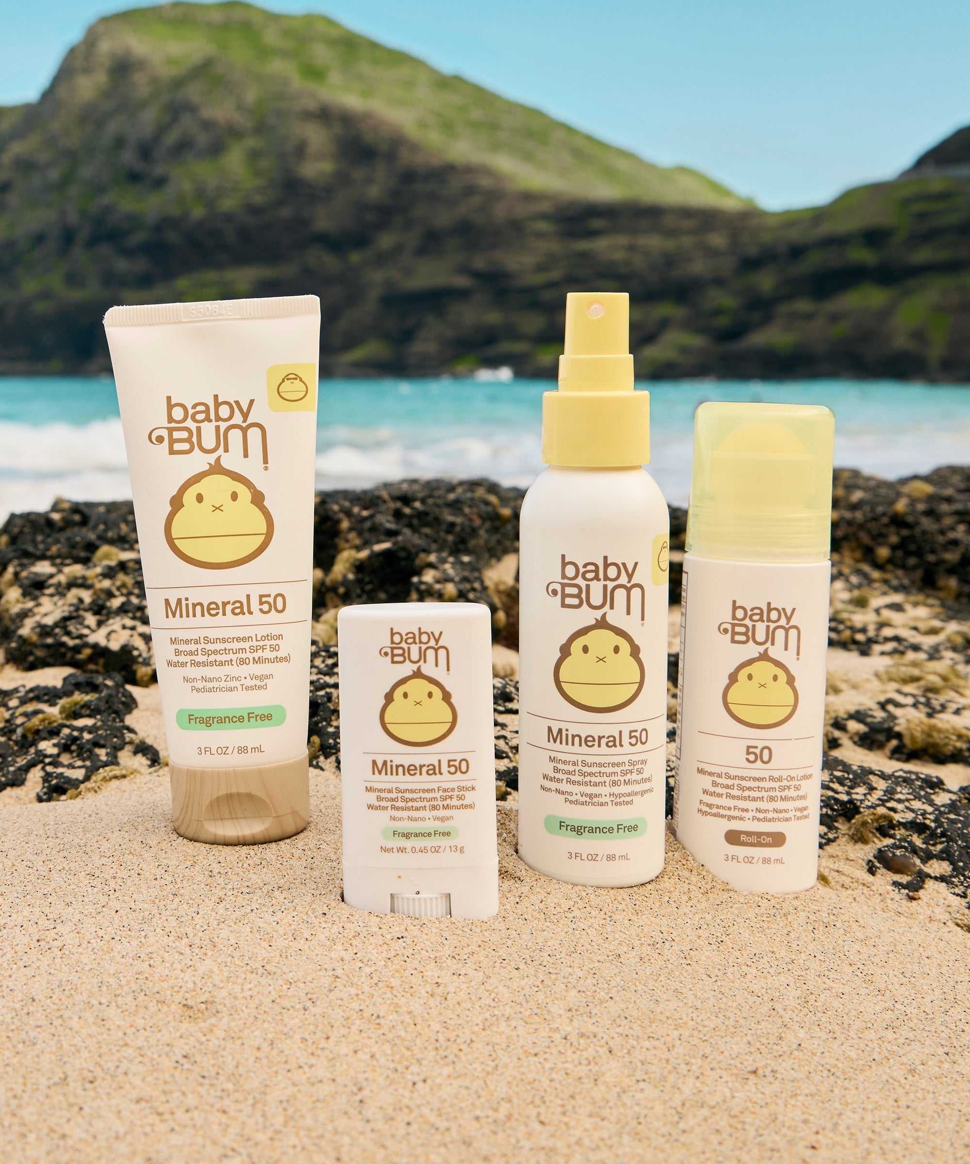 Collection of mineral sunscreen products in white tubes and bottles arranged on beach sand