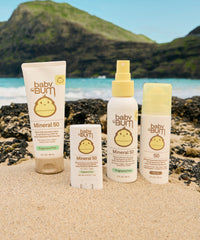 Collection of mineral sunscreen products in white tubes and bottles arranged on beach sand