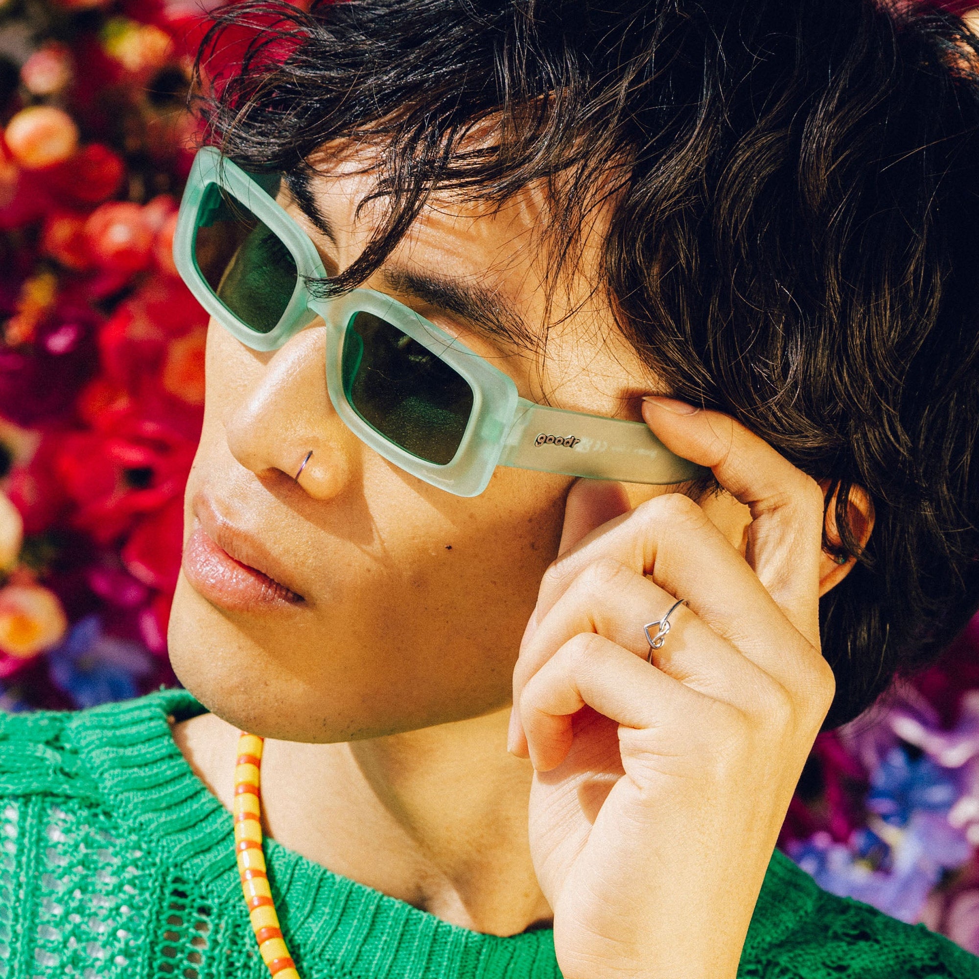 Mint green rectangular sunglasses worn by person with dark hair in lifestyle photo