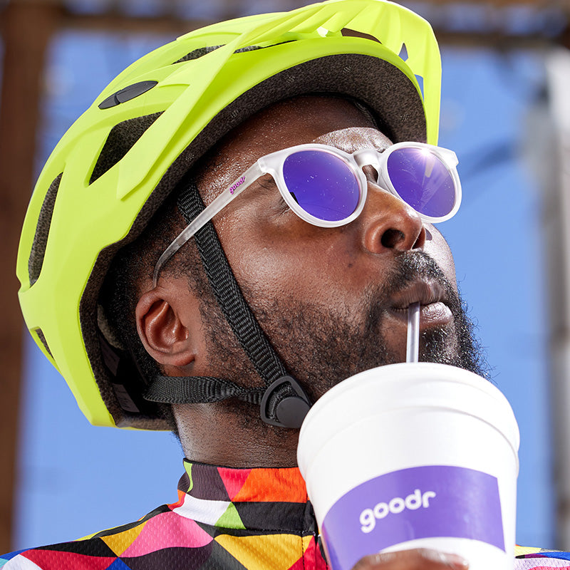 White framed sunglasses with purple mirrored lenses worn by cyclist with helmet