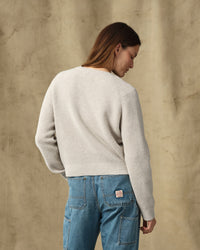 Women's waffle knit crewneck sweater in cream, back view, paired with light wash jeans