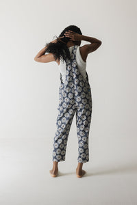 Women's overalls with white daisy pattern on navy background, shown from behind