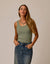 Woman wearing sage green ribbed tank top with denim skirt in studio setting