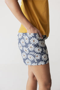 Women's shorts with white daisy floral pattern on light blue background, side view