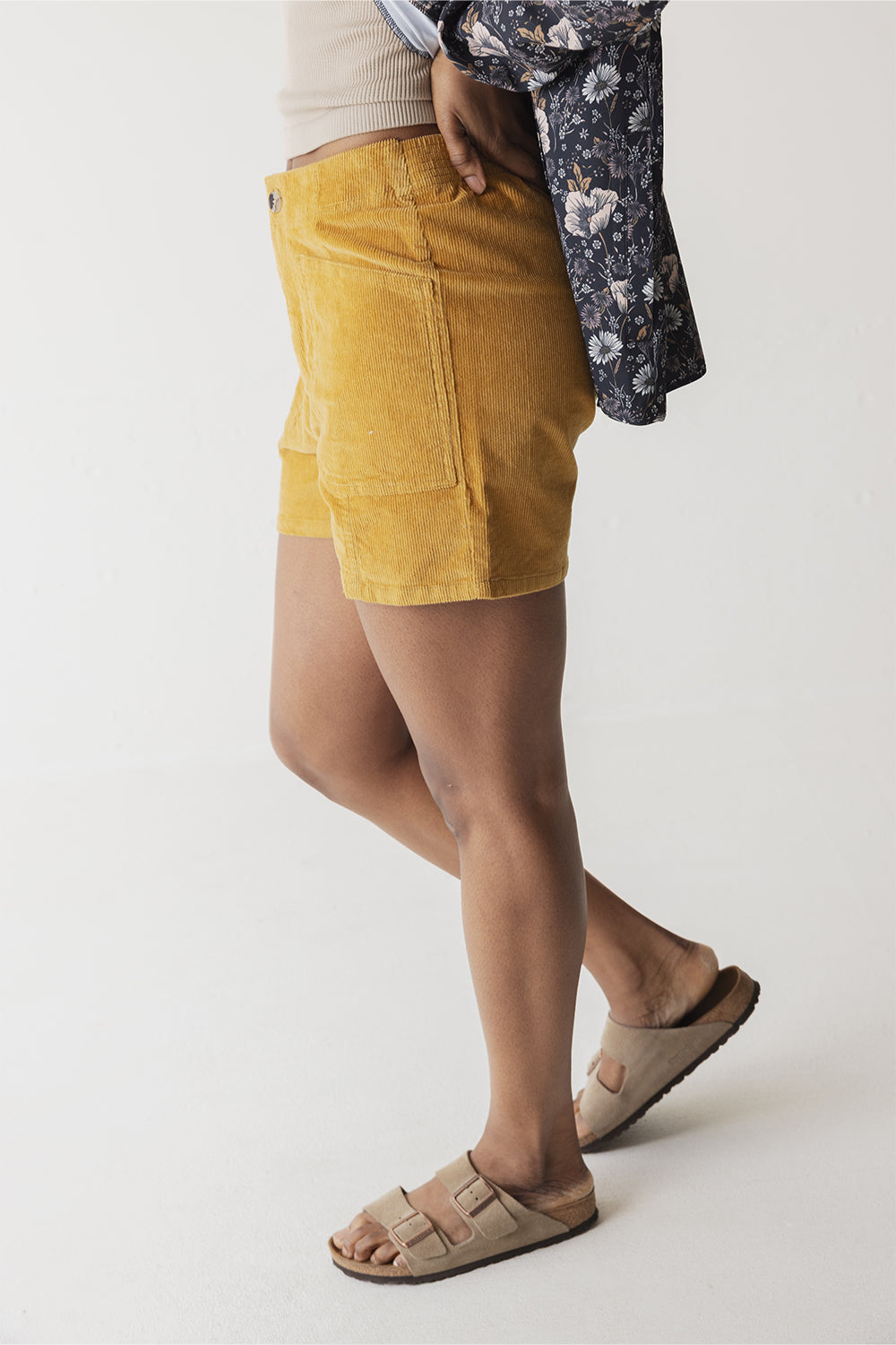 Mustard yellow corduroy shorts with side pockets shown from side angle