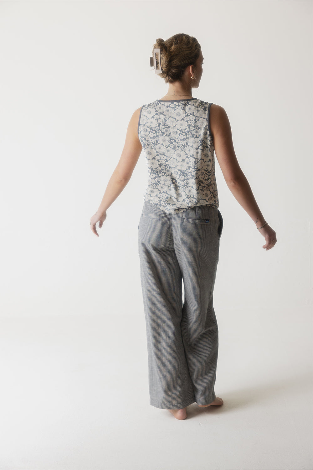 Gray pinstriped wide-leg pants shown from behind on model in studio setting