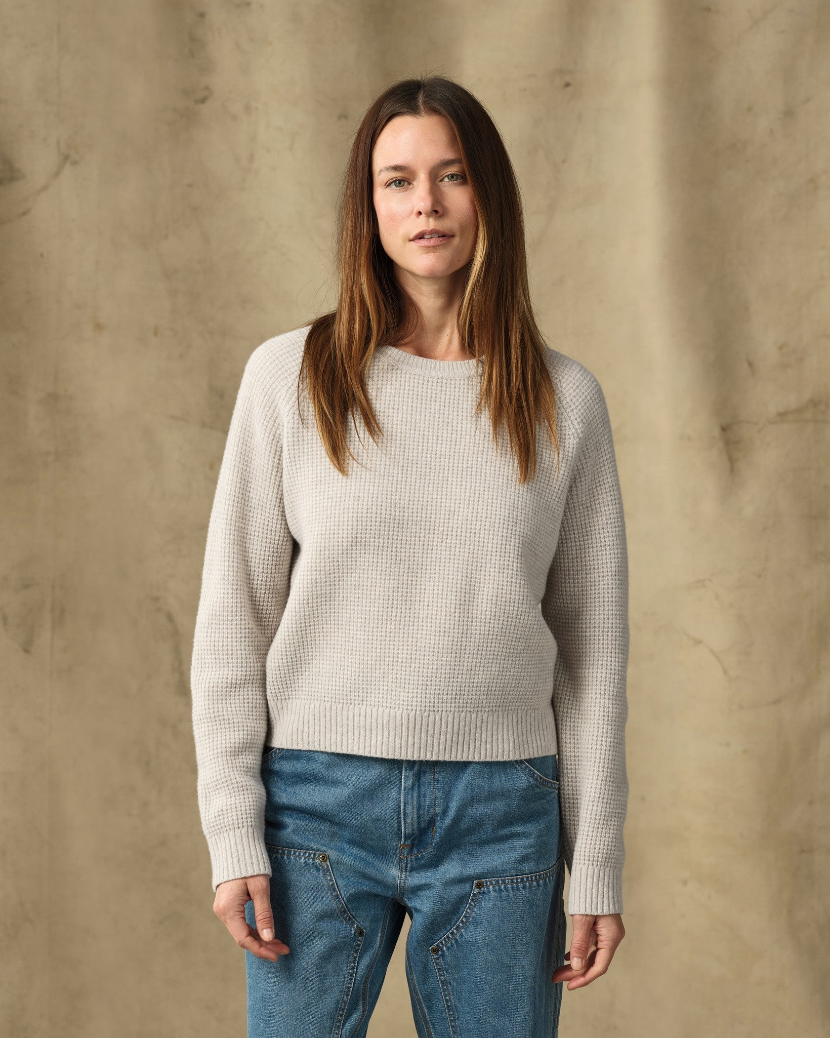 Women's waffle knit crewneck sweater in light cream, front view on model with jeans
