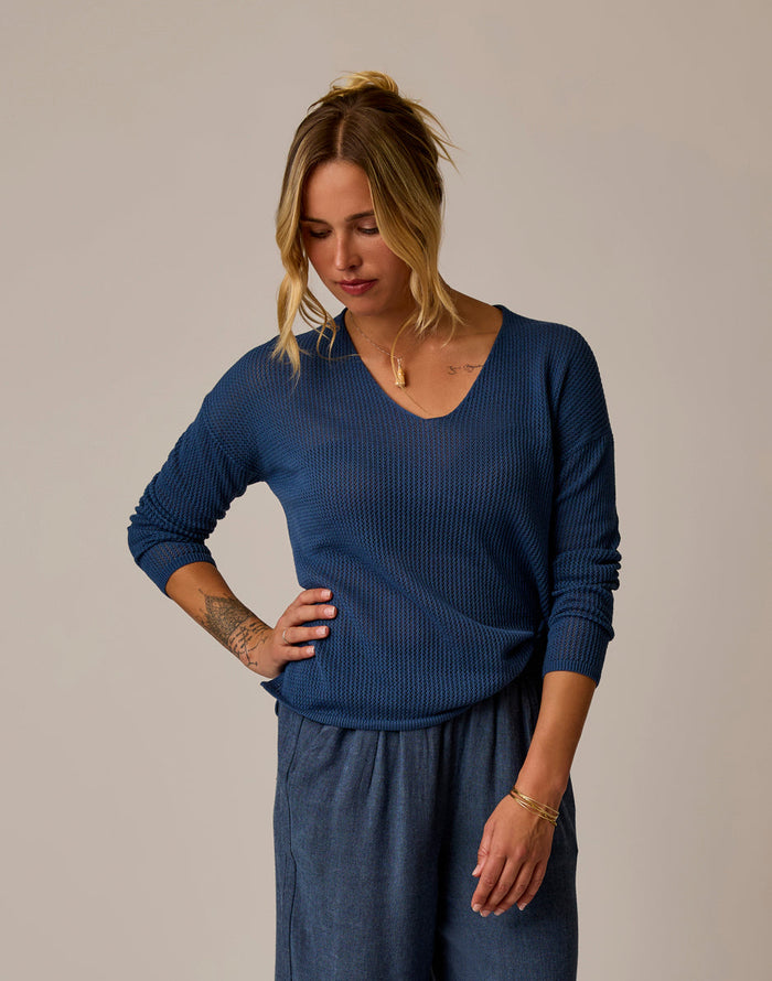 Woman wearing navy blue mesh pullover with v-neck and long sleeves, front view