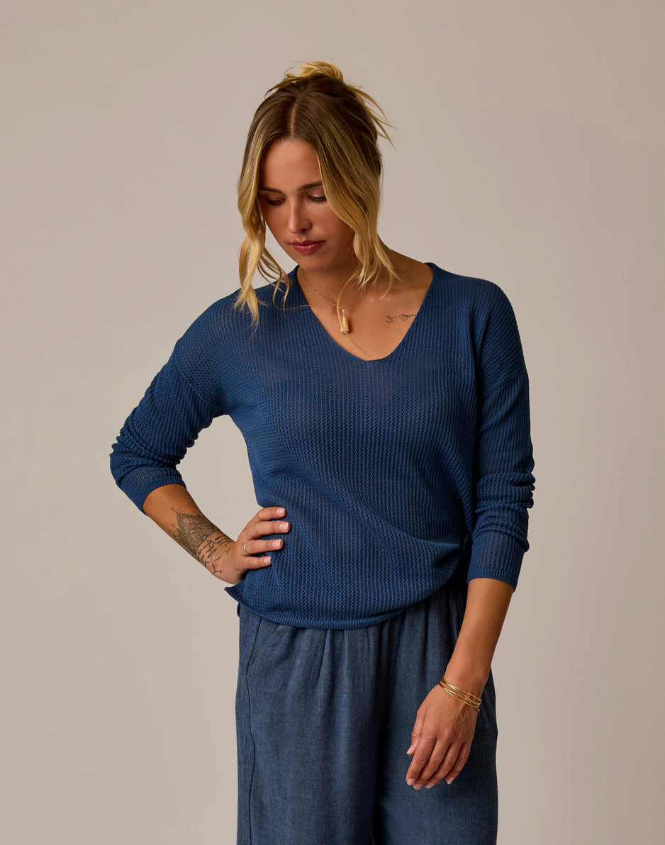 Woman wearing navy blue mesh pullover with v-neck and long sleeves, front view