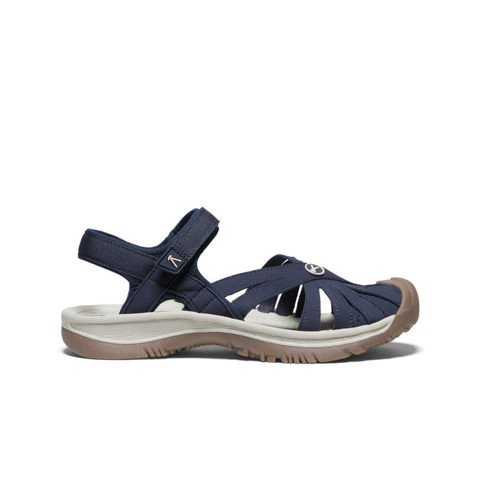 Navy blue women's closed-toe sandal with ankle strap and beige sole, side view