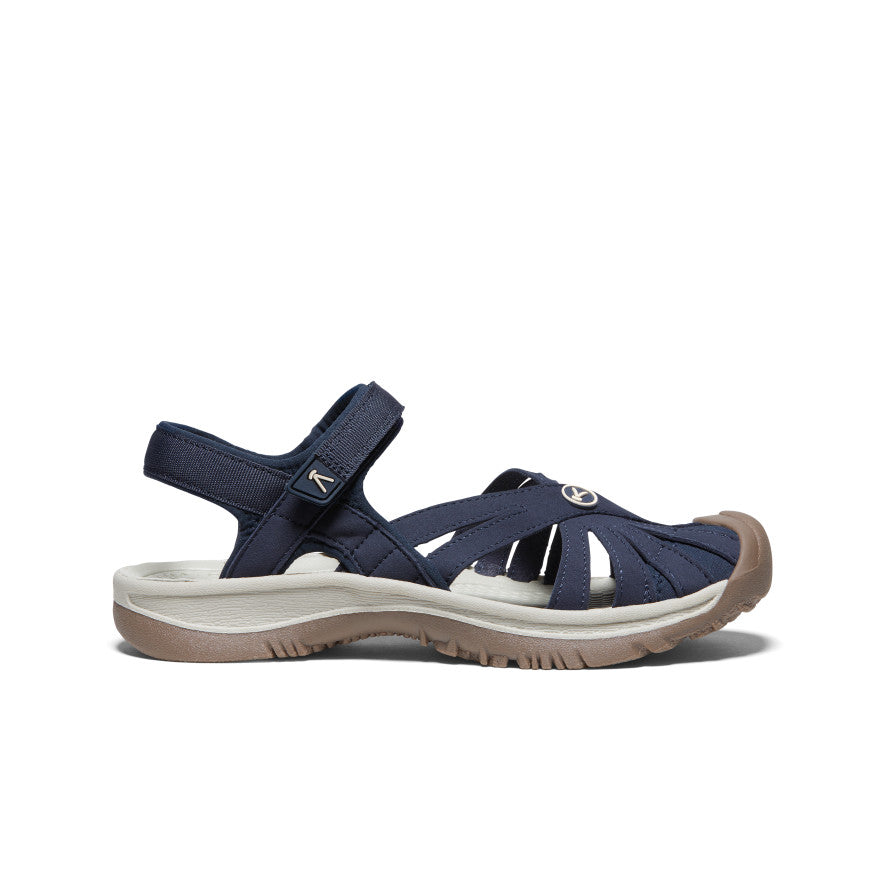 Navy blue women's closed-toe sandal with ankle strap and beige sole, side view