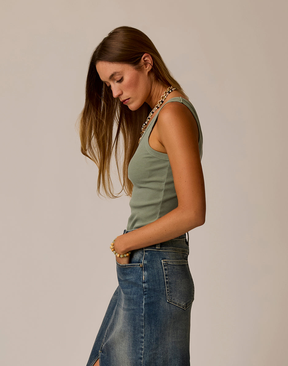 Sage green ribbed tank top worn with denim skirt, side view showing fitted silhouette