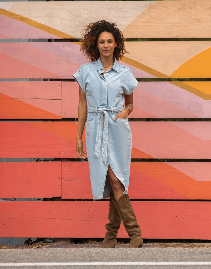 Women's lightweight denim shirt dress with belt, front slit, and knee-high brown boots, front view
