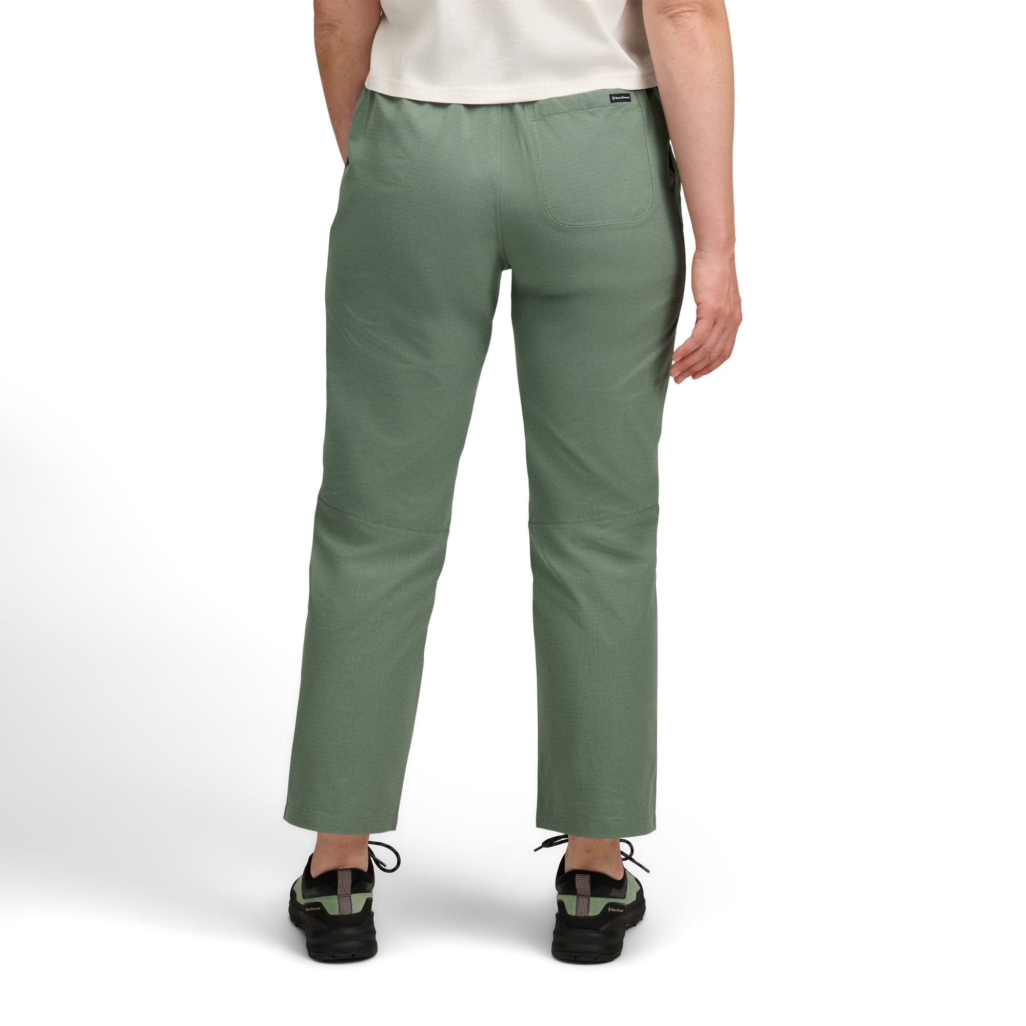 Women's casual pants in sage green color shown from back view with outdoor sneakers