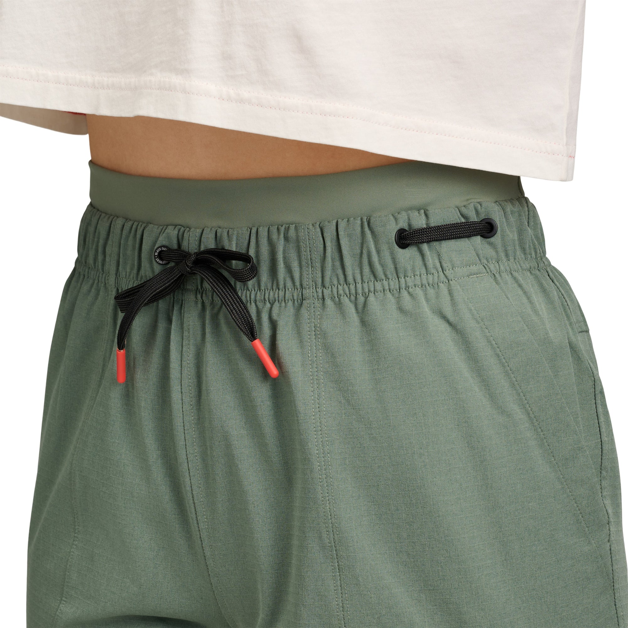 Sage green athletic pants with drawstring waist and side pockets, worn view