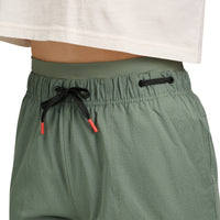 Sage green athletic pants with drawstring waist and side pockets, worn view