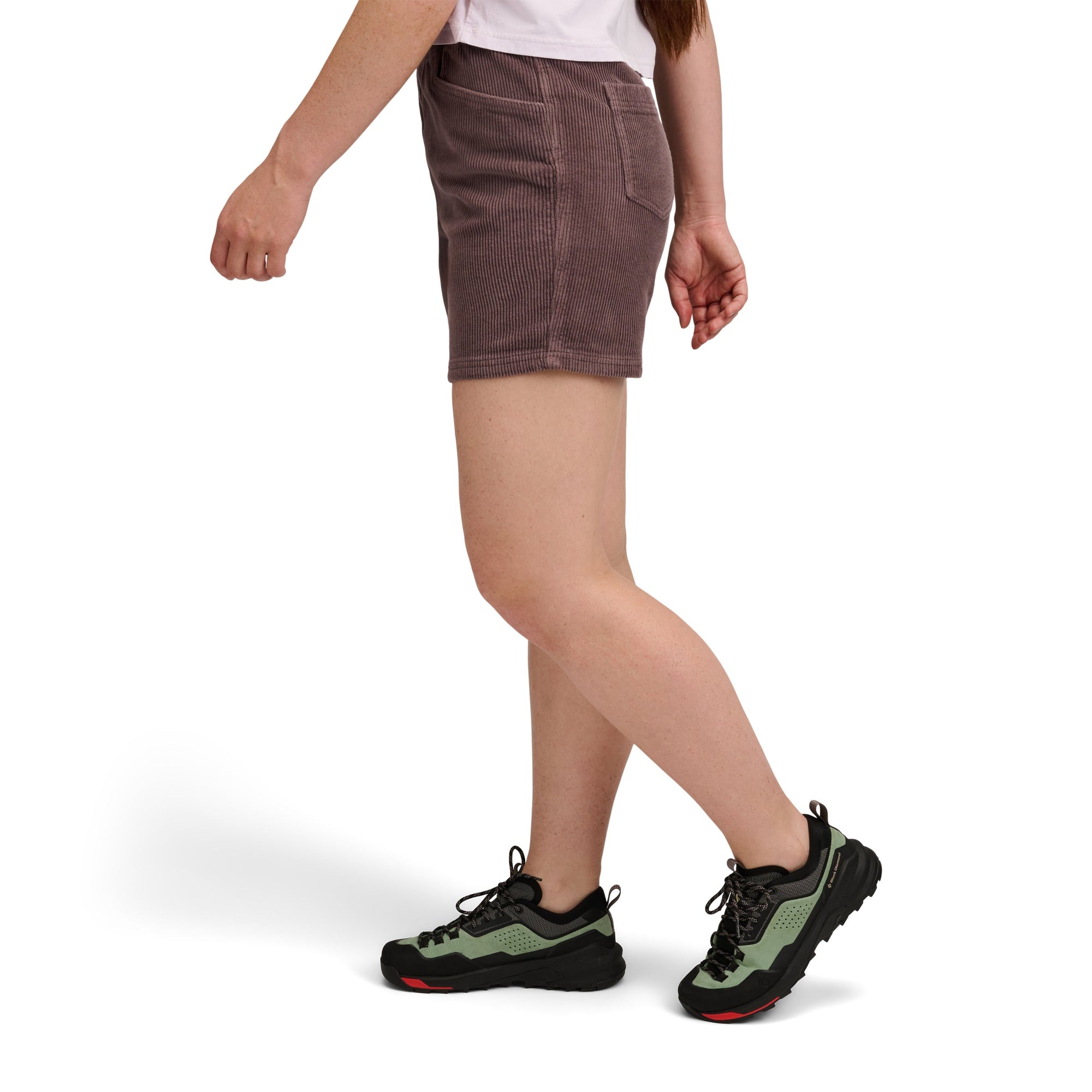 Corduroy shorts with side pockets shown on model with hiking shoes, side view