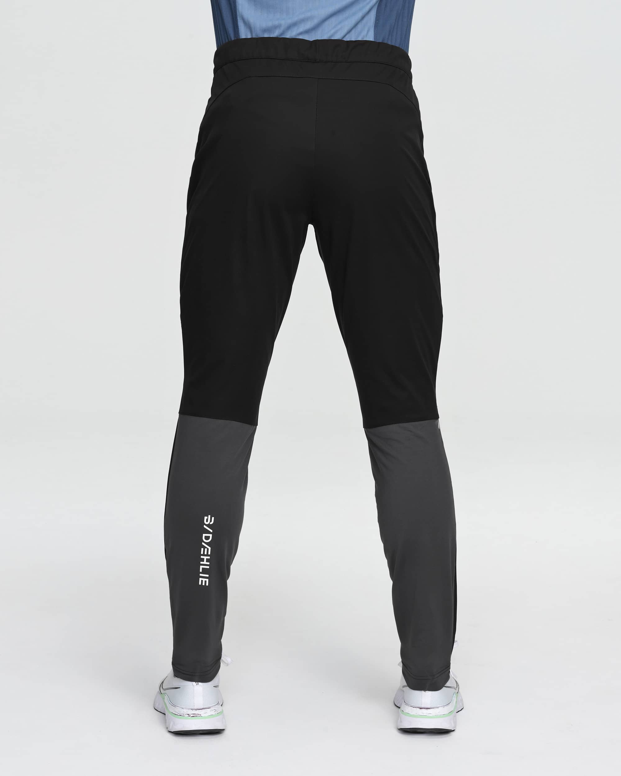 Men's slim-fit athletic pants, back view, black with dark gray lower leg panels