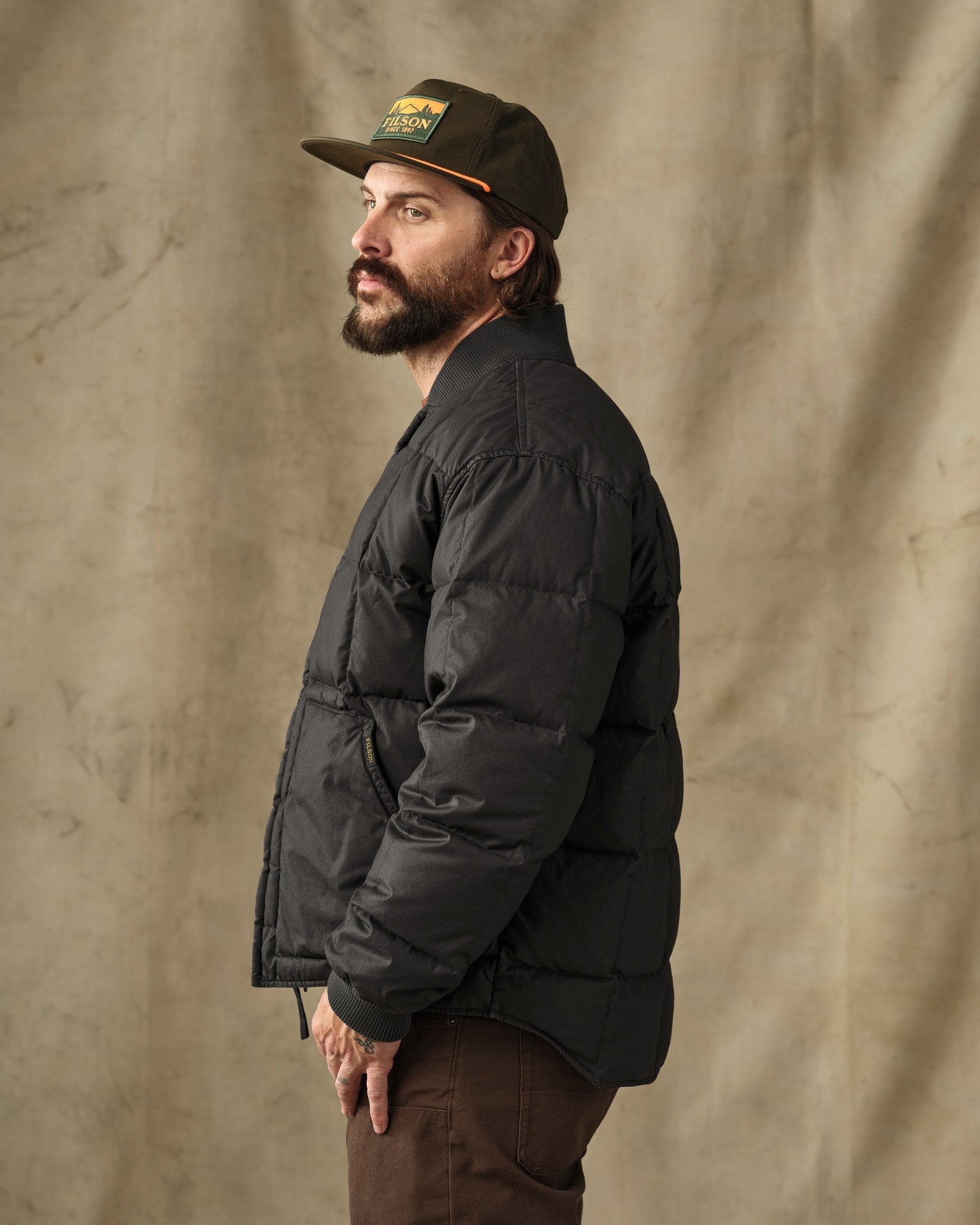 Men's black quilted down puffer jacket, side profile view, ribbed collar and cuffs