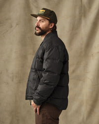 Men's black quilted down puffer jacket, side profile view, ribbed collar and cuffs