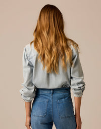 Women's lightweight denim shirt back view, long sleeves rolled at cuffs, paired with blue jeans