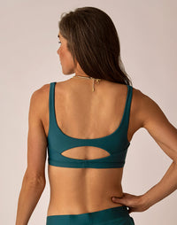 Dark teal compression sports bra with cutout back detail, shown from behind