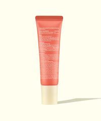 Coral-colored tinted lip balm tube with white cap displayed on neutral background