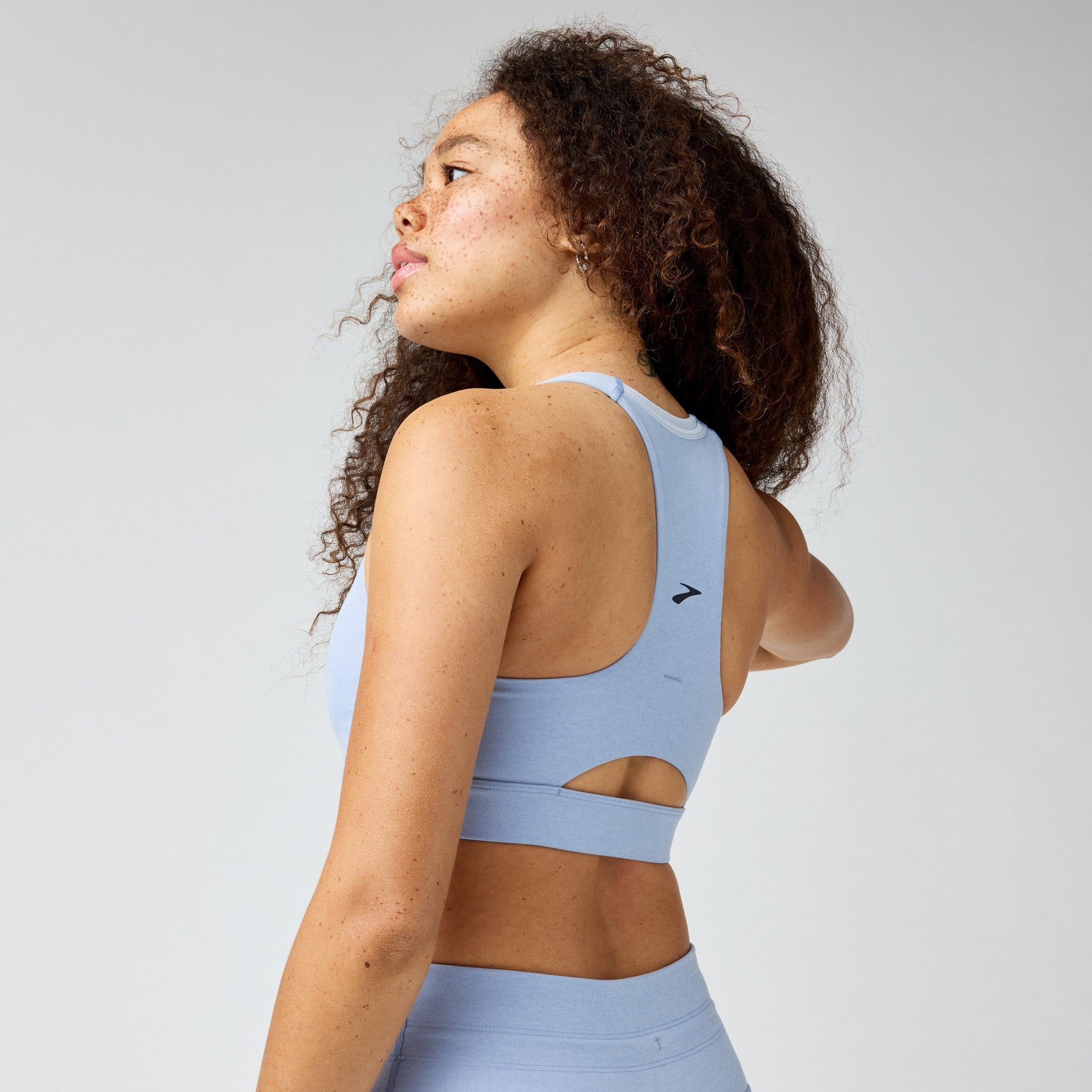 Light blue sports bra with cutout back detail, shown from rear three-quarter view