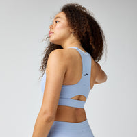 Light blue sports bra with cutout back detail, shown from rear three-quarter view