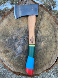 Camp hatchet with steel head and colorful striped wooden handle on tree stump