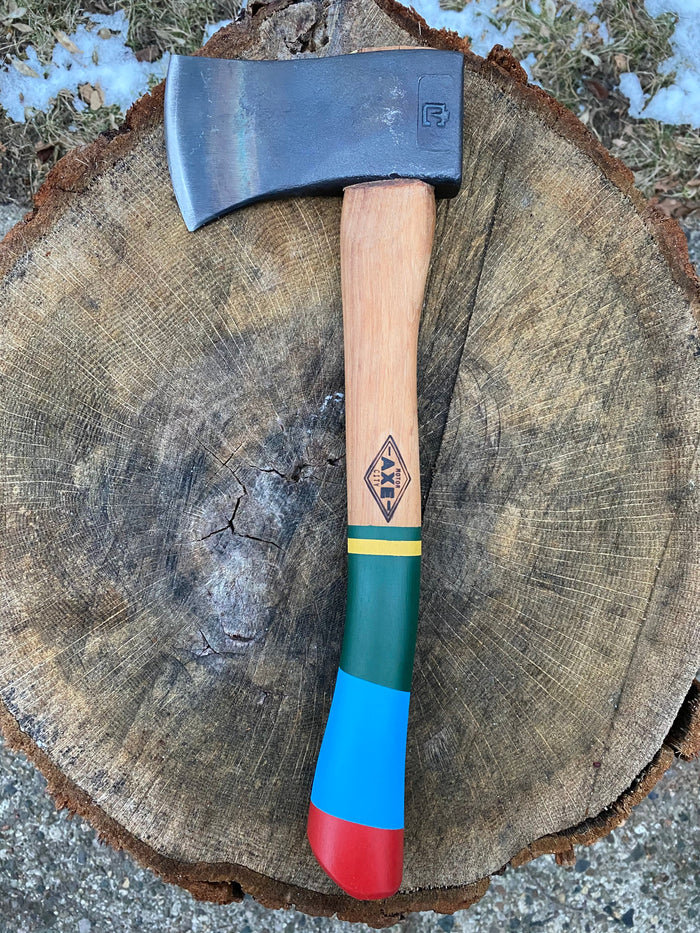 Camp hatchet with steel head and colorful striped wooden handle on tree stump