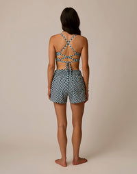 Back view of woman wearing black and white checkered shorts with matching strappy crop top
