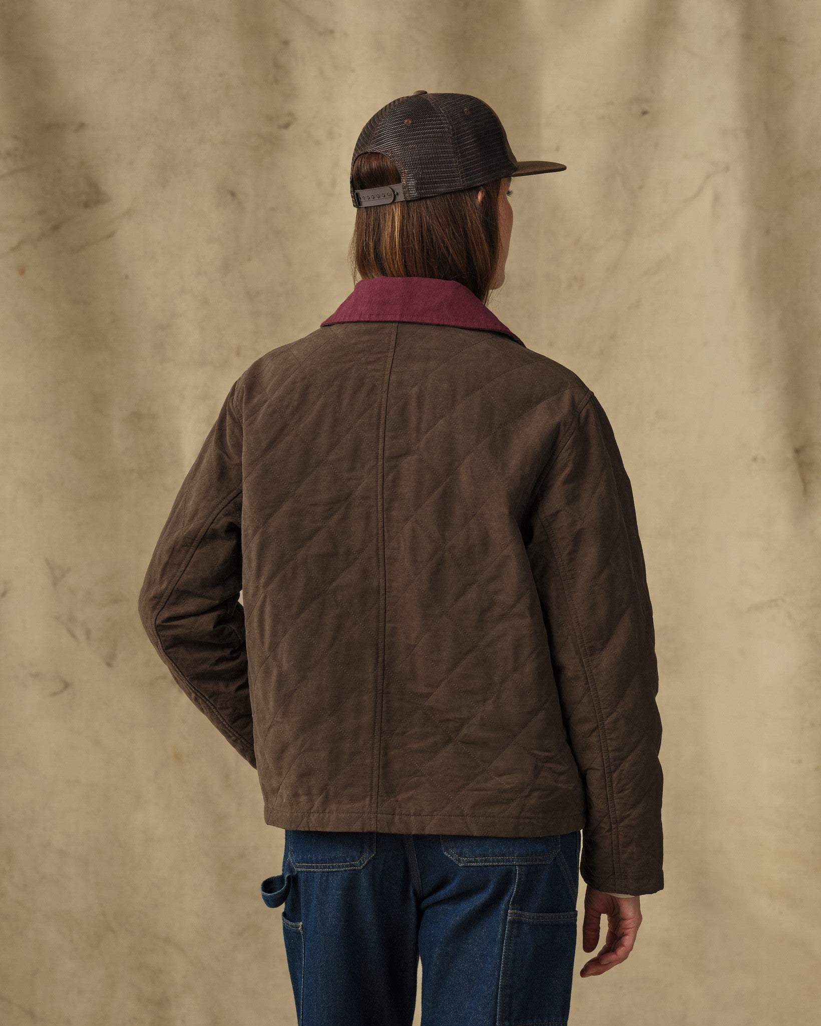Women's quilted jacket in dark brown with burgundy collar, back view, worn with jeans