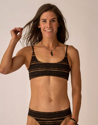 Women's black and gold striped bikini bralette top with thin straps, front view on model