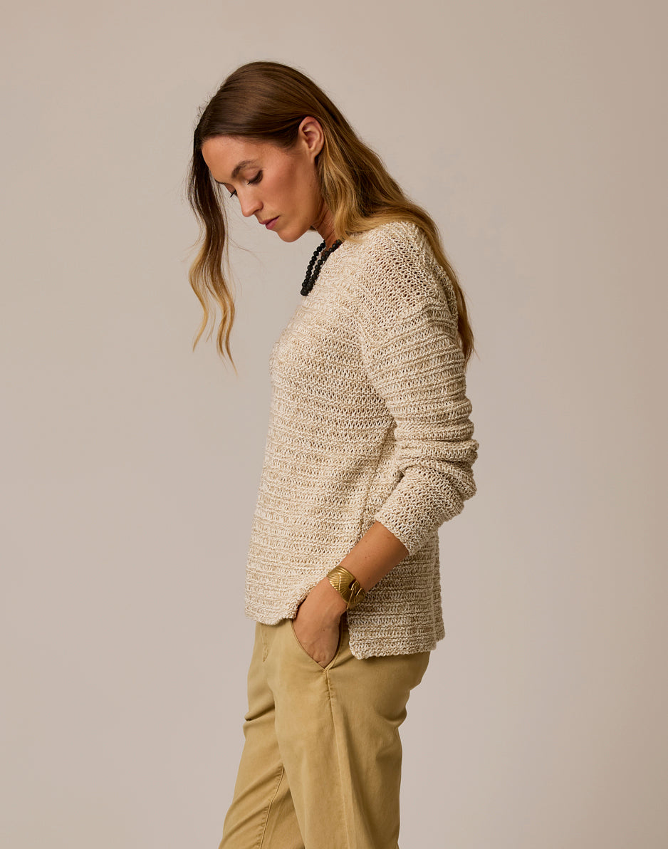 Woman wearing cream colored marled knit sweater with textured horizontal pattern, side profile view
