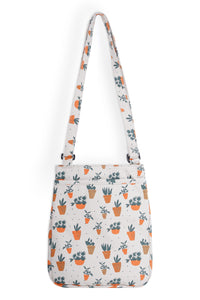 Canvas crossbody bag with adjustable strap featuring orange and brown potted plant pattern on cream background