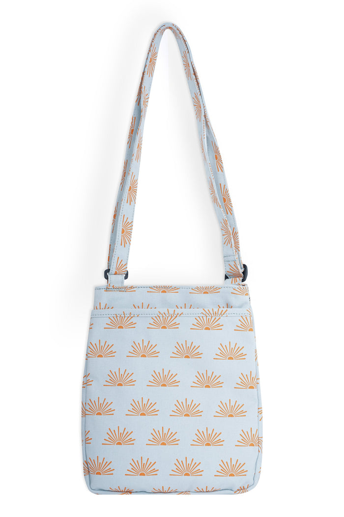 Light blue crossbody bag with orange sunburst pattern and adjustable strap