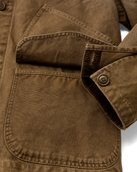Close-up detail of canvas jacket showing chest pocket, sleeve cuff with corduroy trim and button